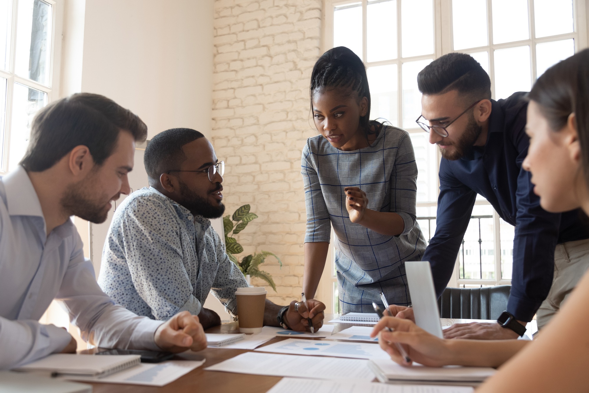 Serious multiracial corporate business team and black leader talk during group briefing